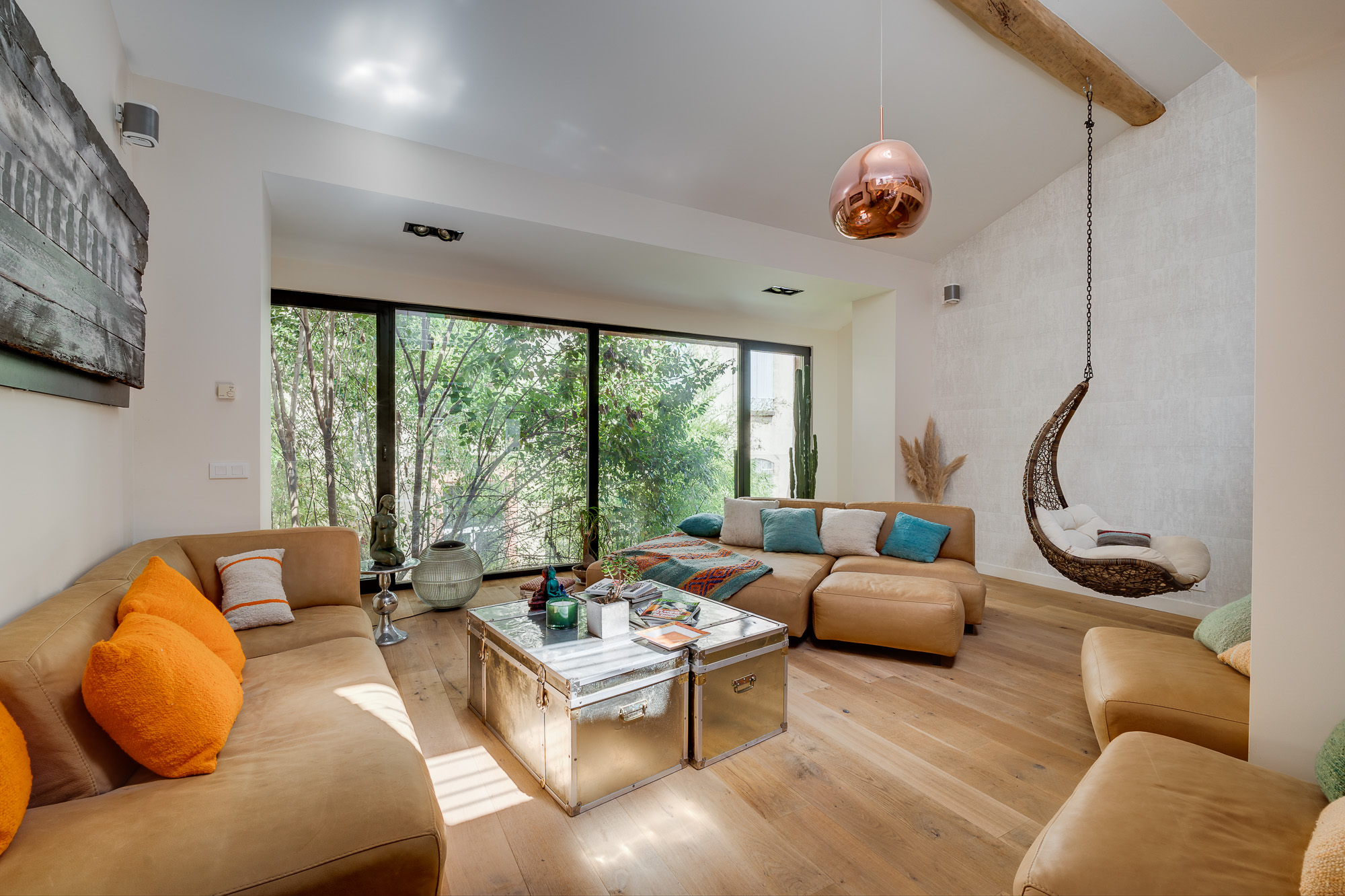 Appartement de luxe Toulouse Pikimo-2 Salon séjour décoré avec canapés en cuir camel, suspension cuivrée et chaise suspendue — appartement de luxe Toulouse — reportage immobilier Pikimo