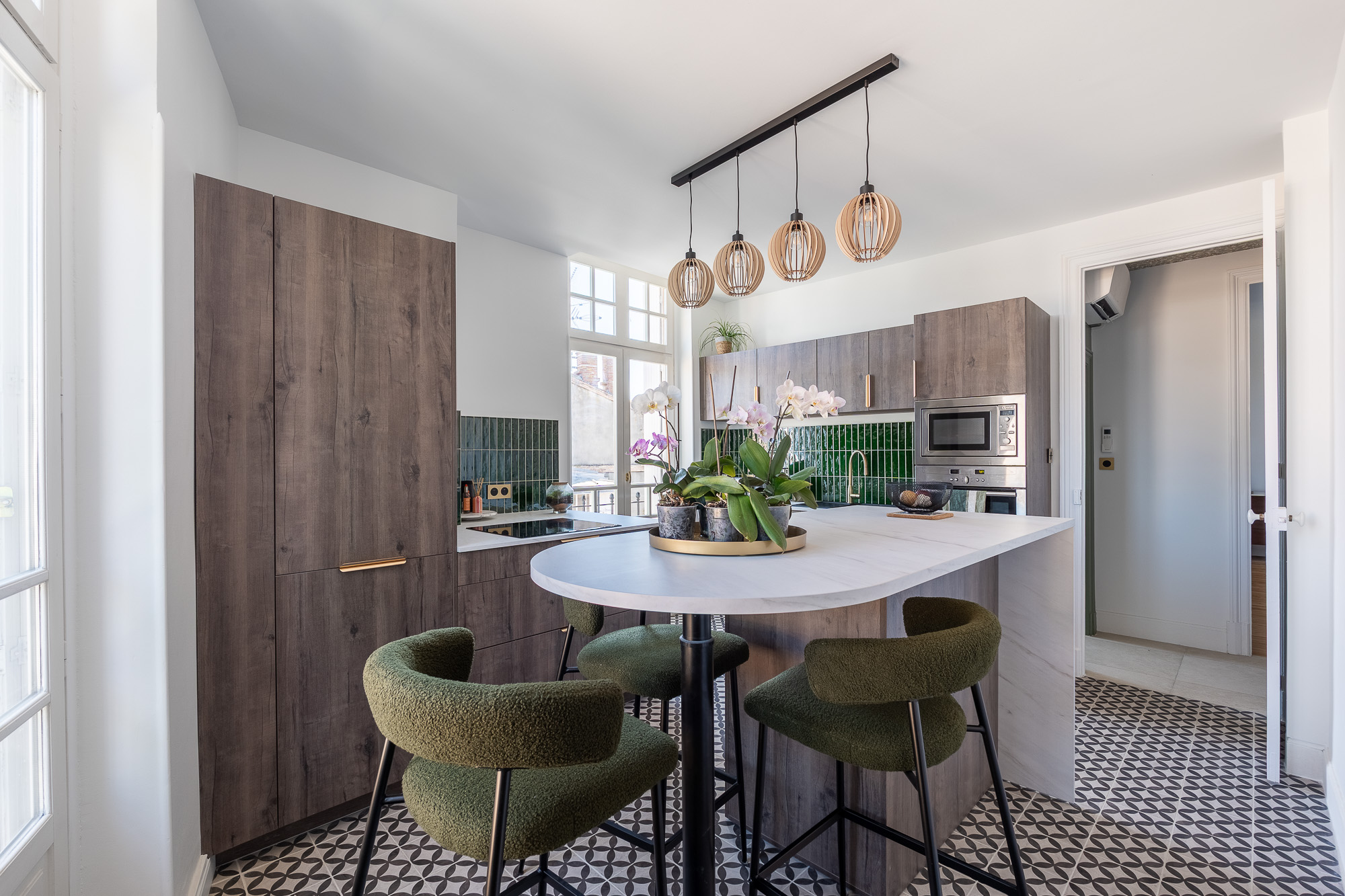 Cuisine rénovée avec îlot central arrondi, carrelage graphique et crédence verte — rénovation appartement Toulouse LM Déco Marylène Laurent — reportage Pikimo