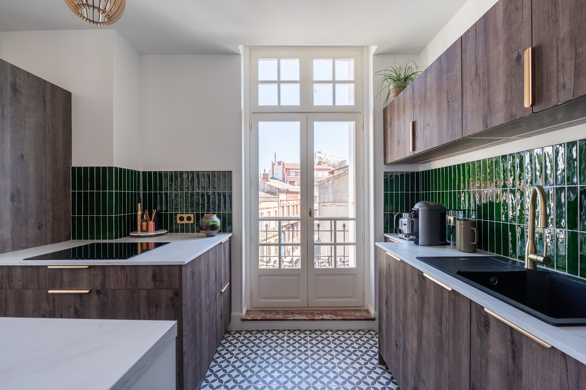 Cuisine en bois foncé avec crédence de carreaux verts et vue sur balcon — rénovation appartement Toulouse LM Déco architecte d'intérieur — photographe Pikimo