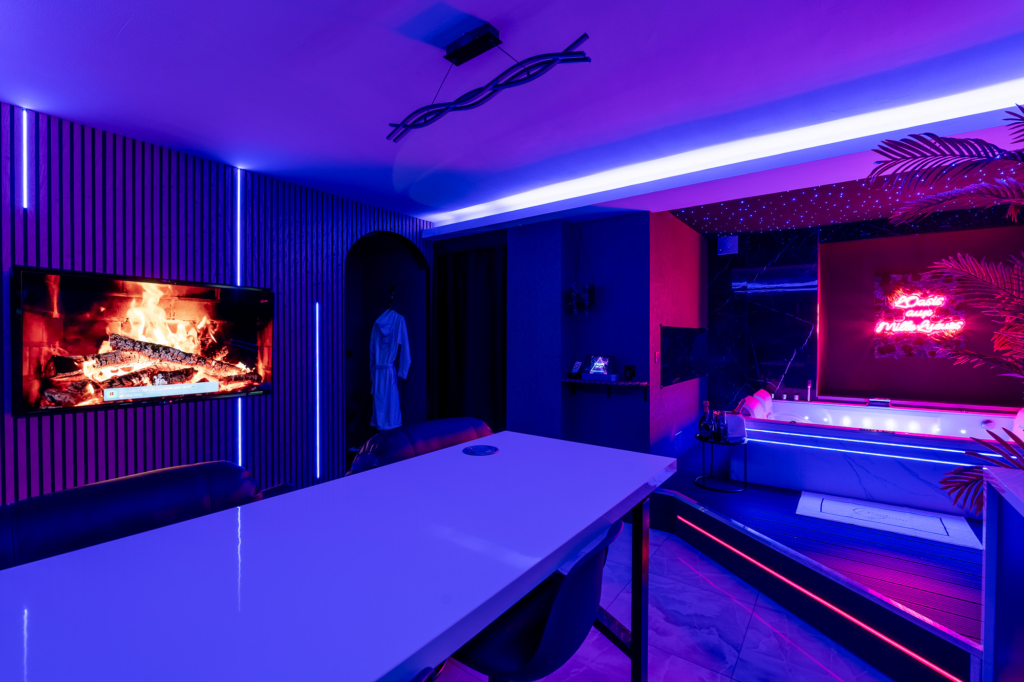 Suite avec jacuzzi ambiance néon bleu et cheminée TV — L'Oasis aux Mille Lueurs Airbnb Toulouse