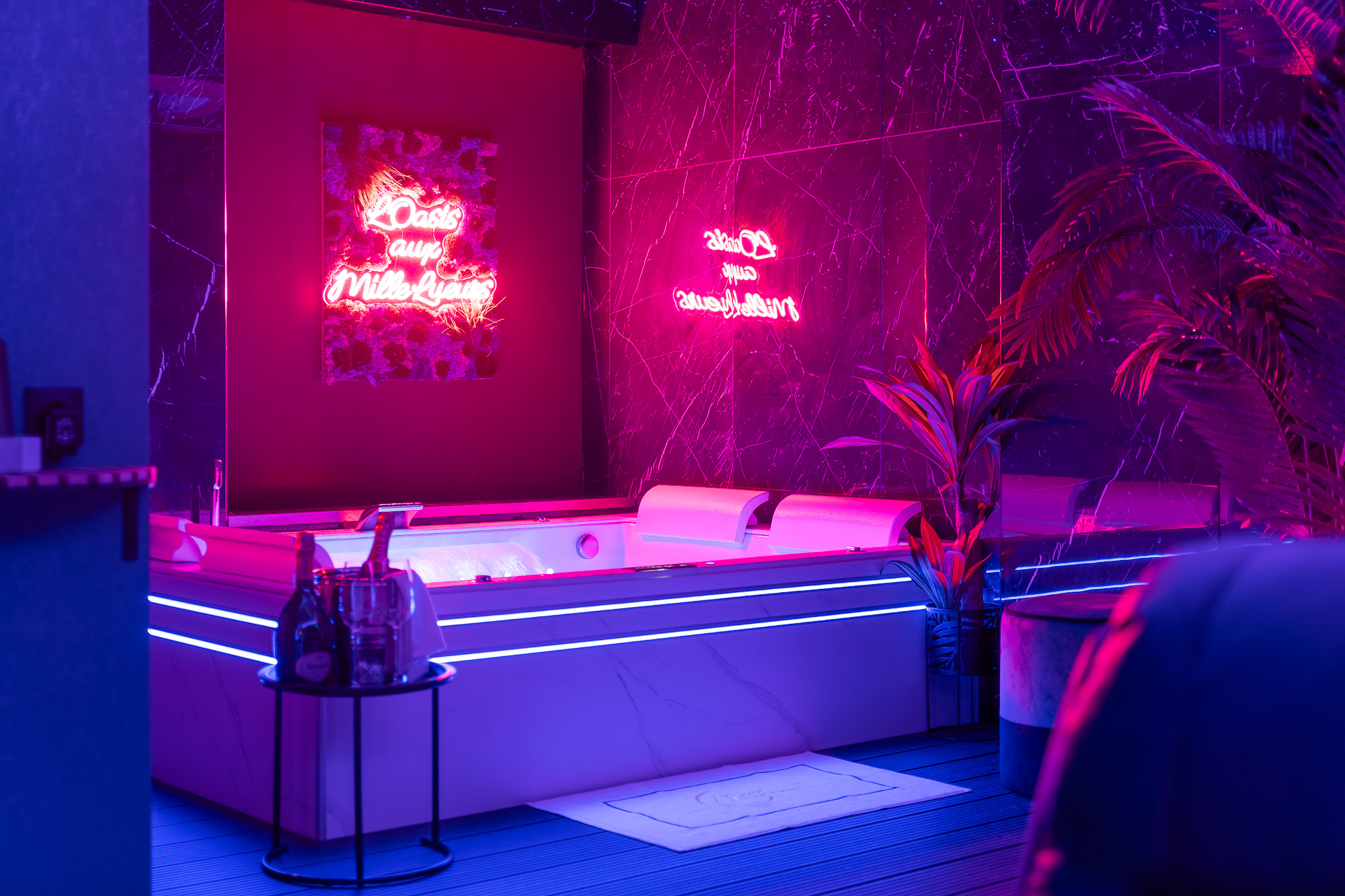 Jacuzzi balnéo néon rose et marbre noir — L'Oasis aux Mille Lueurs location romantique Toulouse