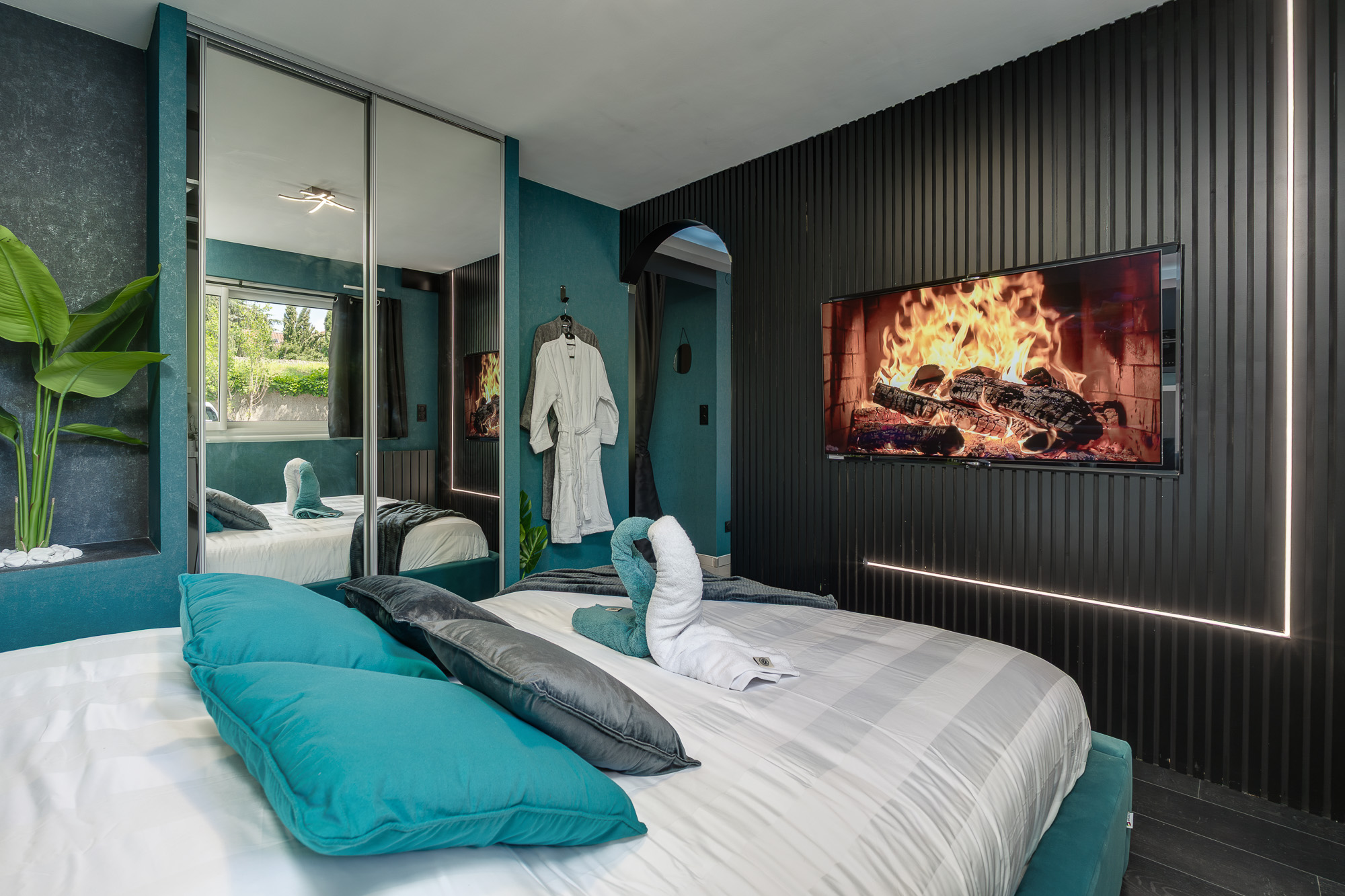 Chambre mur tasseaux noirs et TV cheminée — L'Oasis aux Mille Lueurs Airbnb Toulouse