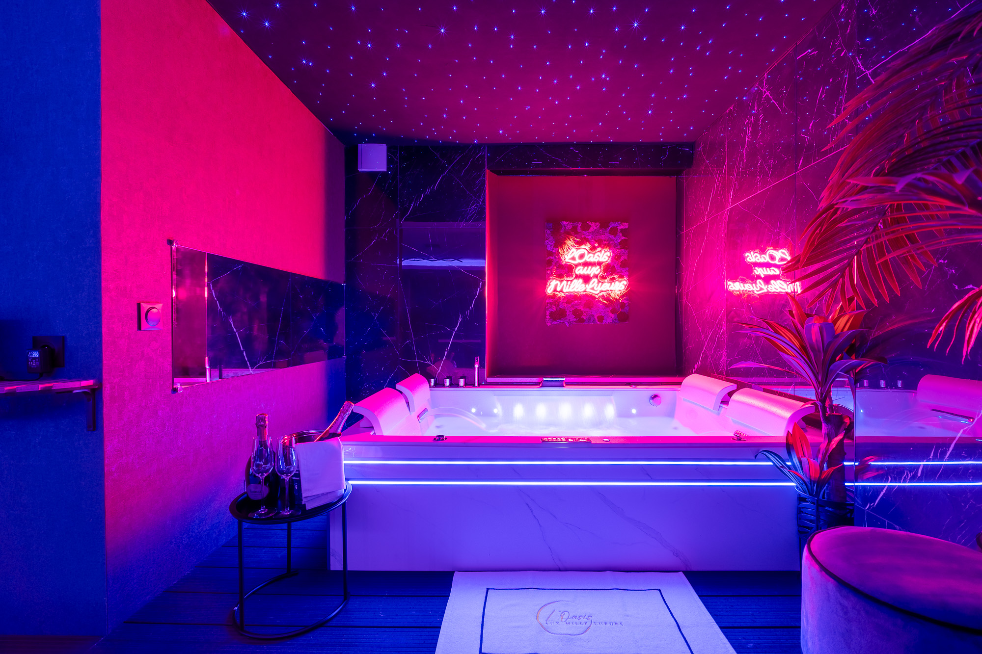 Jacuzzi spa plafond étoilé ambiance rose et bleu — L'Oasis aux Mille Lueurs love room Toulouse