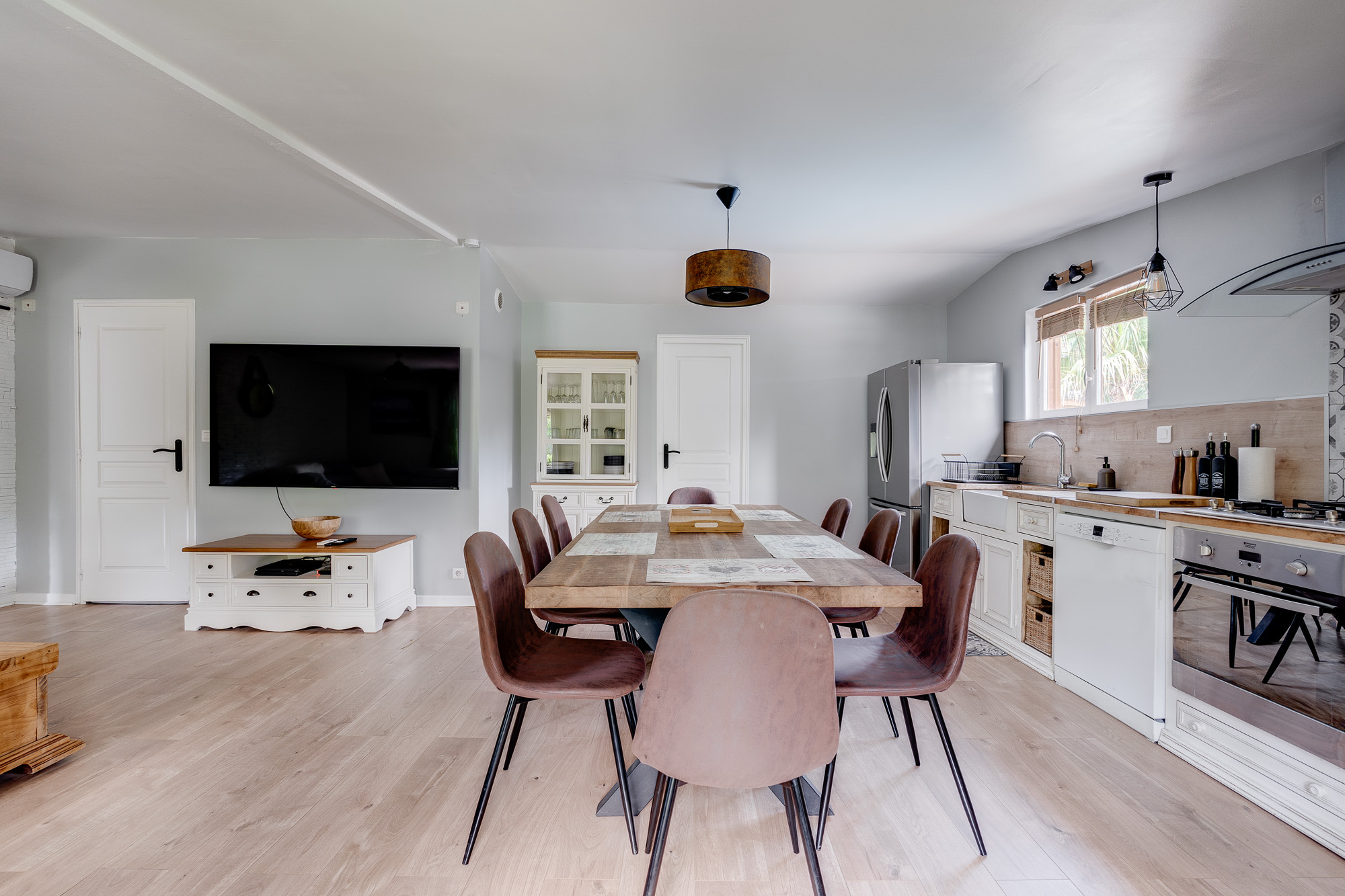 Salle à manger avec grande table en bois et télévision murale