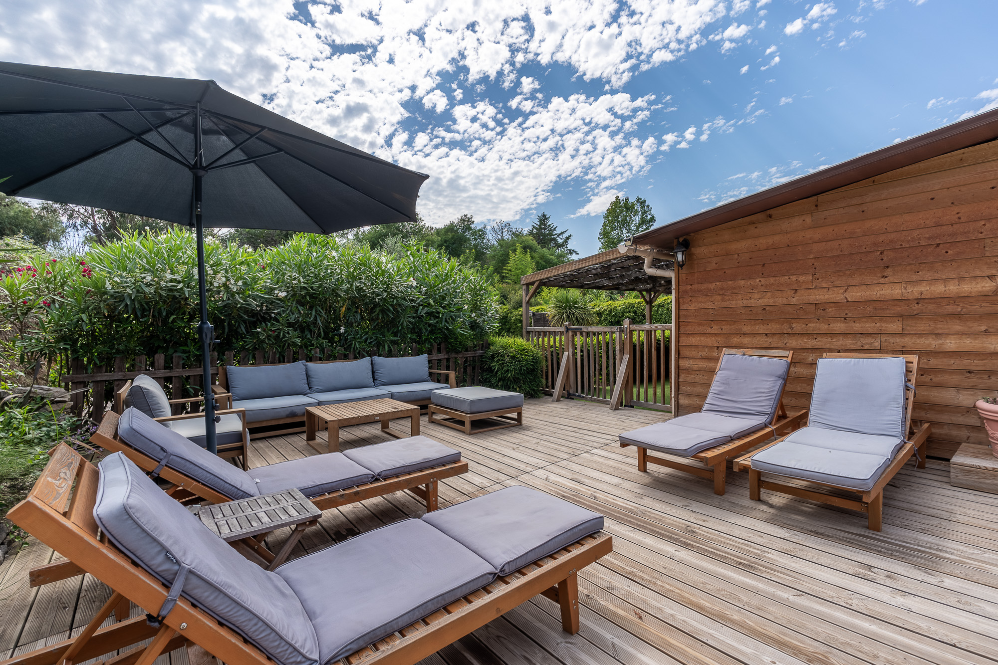 errasse en bois avec transats, salon de jardin et parasol du gîte