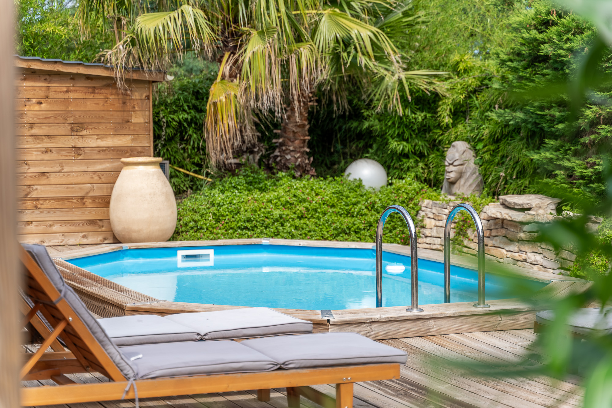 Piscine en bois entourée de palmiers et végétation méditerranéenne