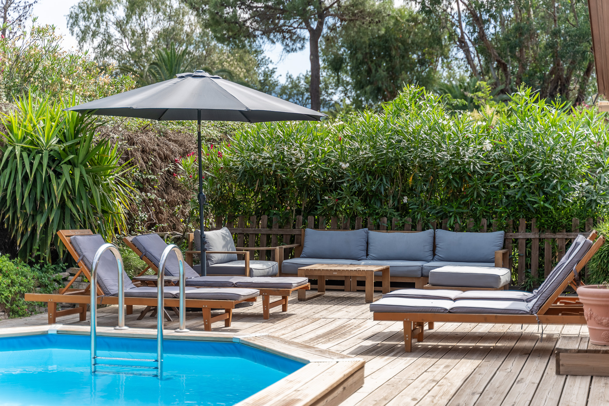 Transats et canapé d'extérieur au bord de la piscine du gîte