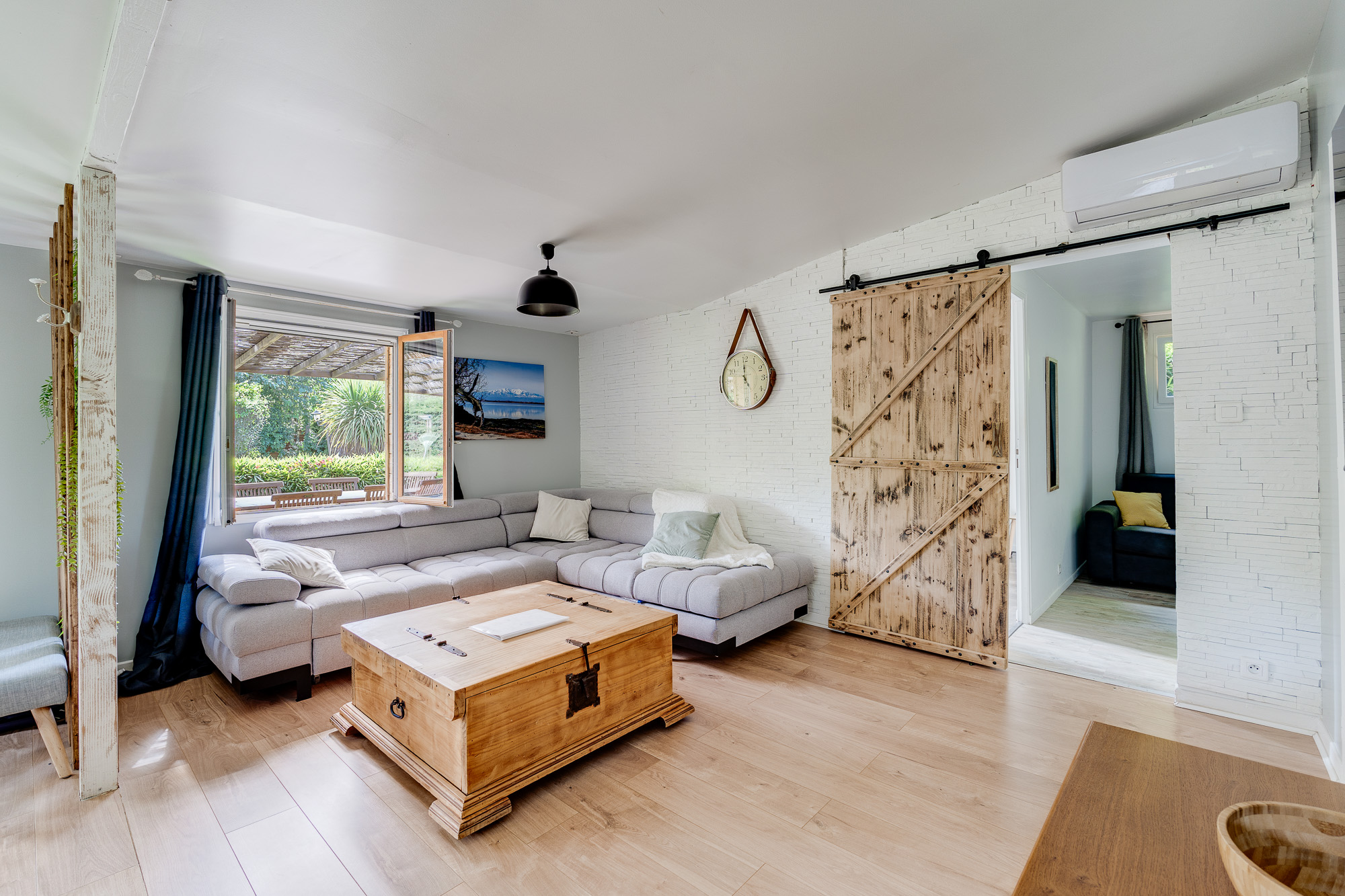 Salon avec canapé d'angle gris et porte coulissante en bois