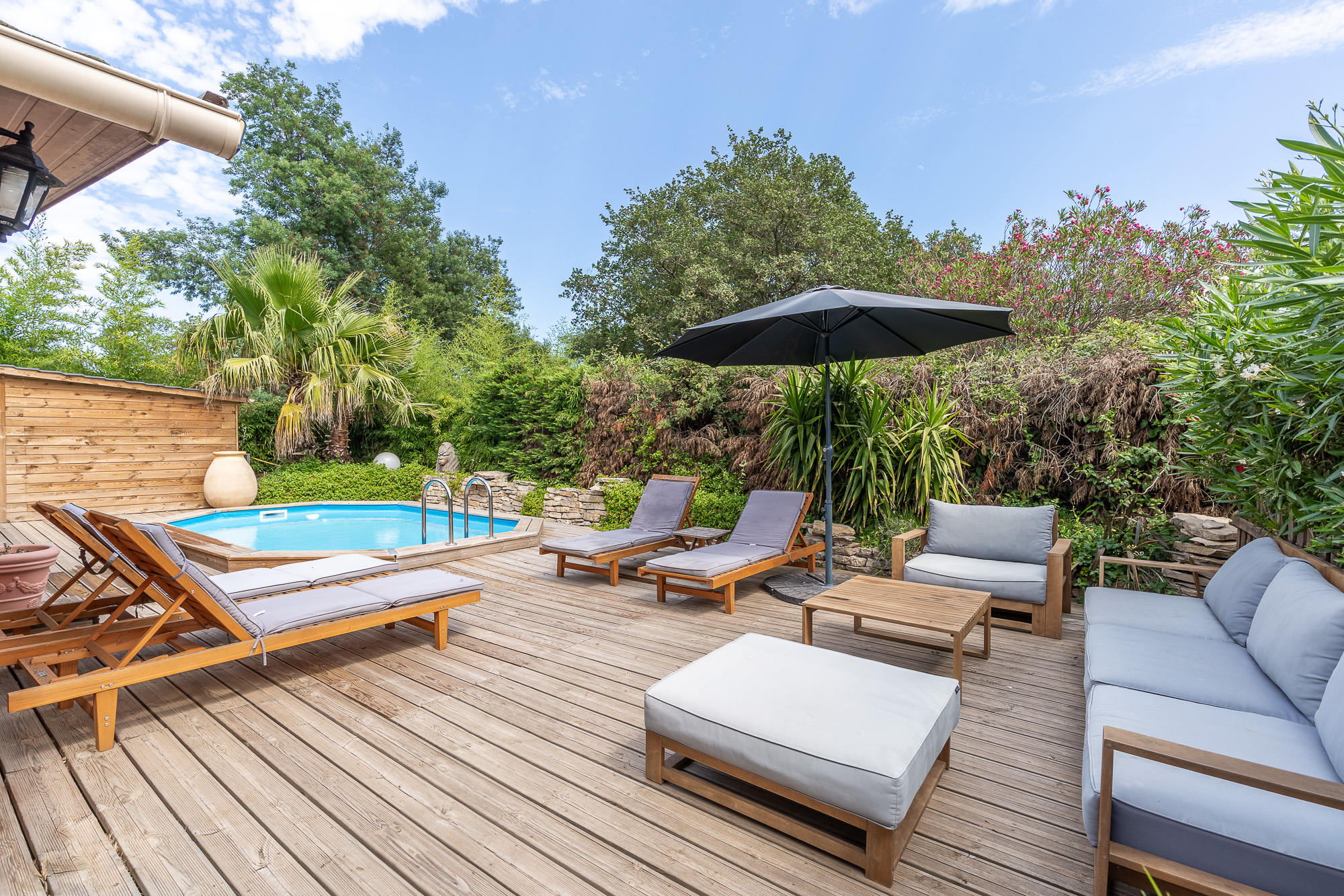 Terrasse en bois avec piscine, transats et mobilier de jardin