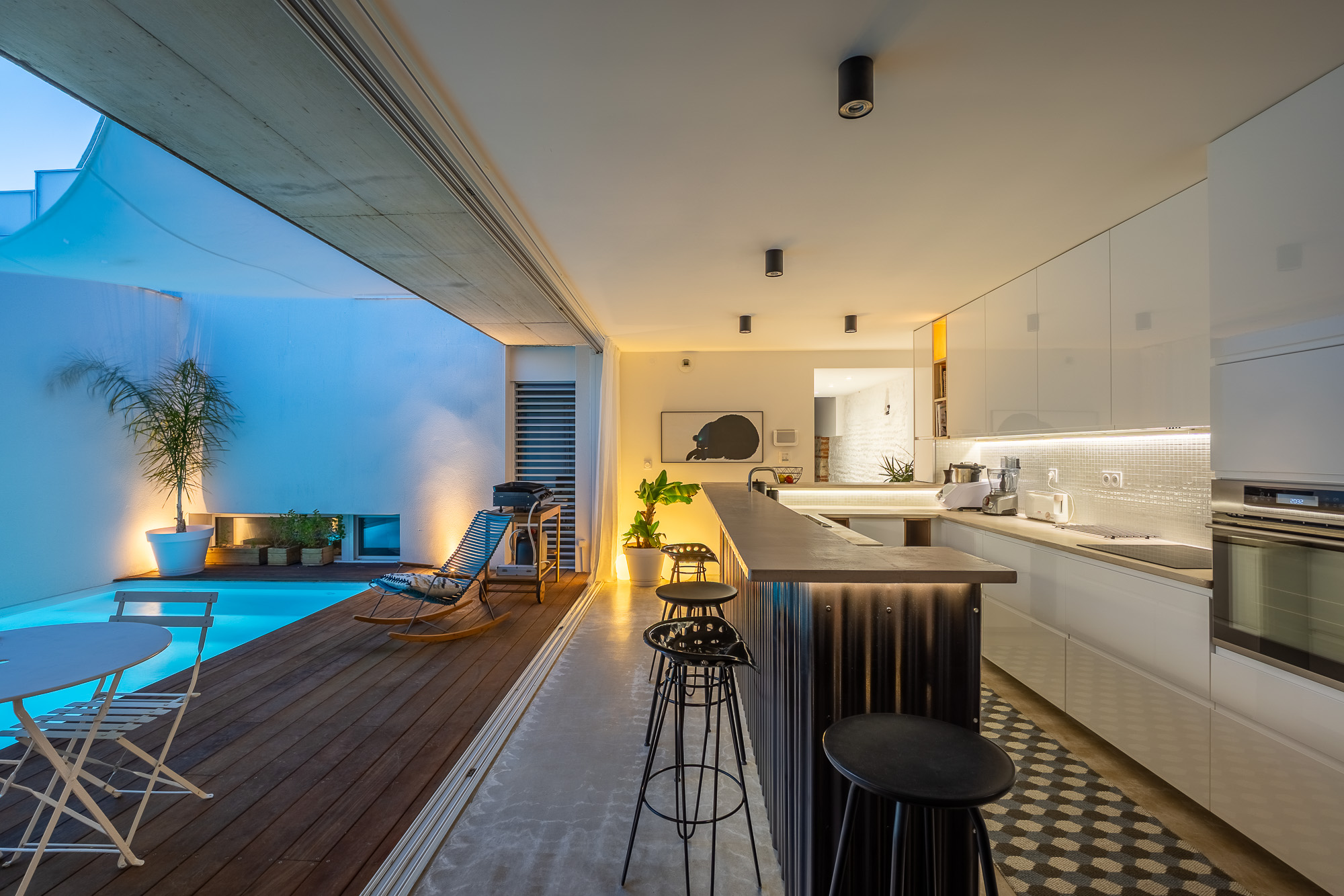 Maison de luxe Toulouse Pikimo photographe haut de gamme-4 Cuisine design ouverte sur piscine illuminée de nuit avec îlot central et carrelage graphique — maison de luxe Toulouse — photographe haut de gamme Pikimo