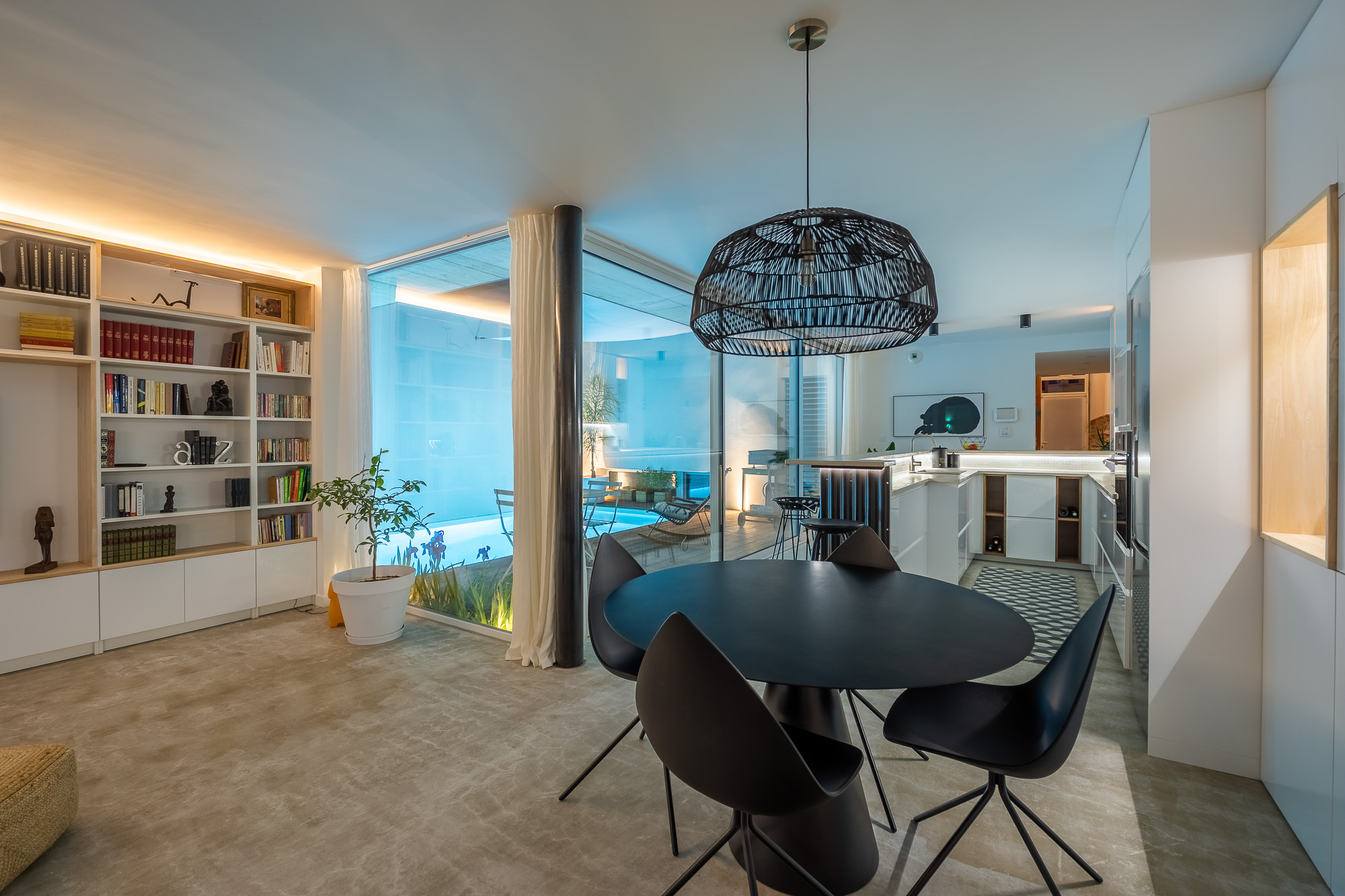 Maison de luxe Toulouse Pikimo photographe haut de gamme Salle à manger avec bibliothèque sur mesure et vue sur piscine intérieure illuminée — maison de luxe Toulouse — reportage immobilier haut de gamme Pikimo