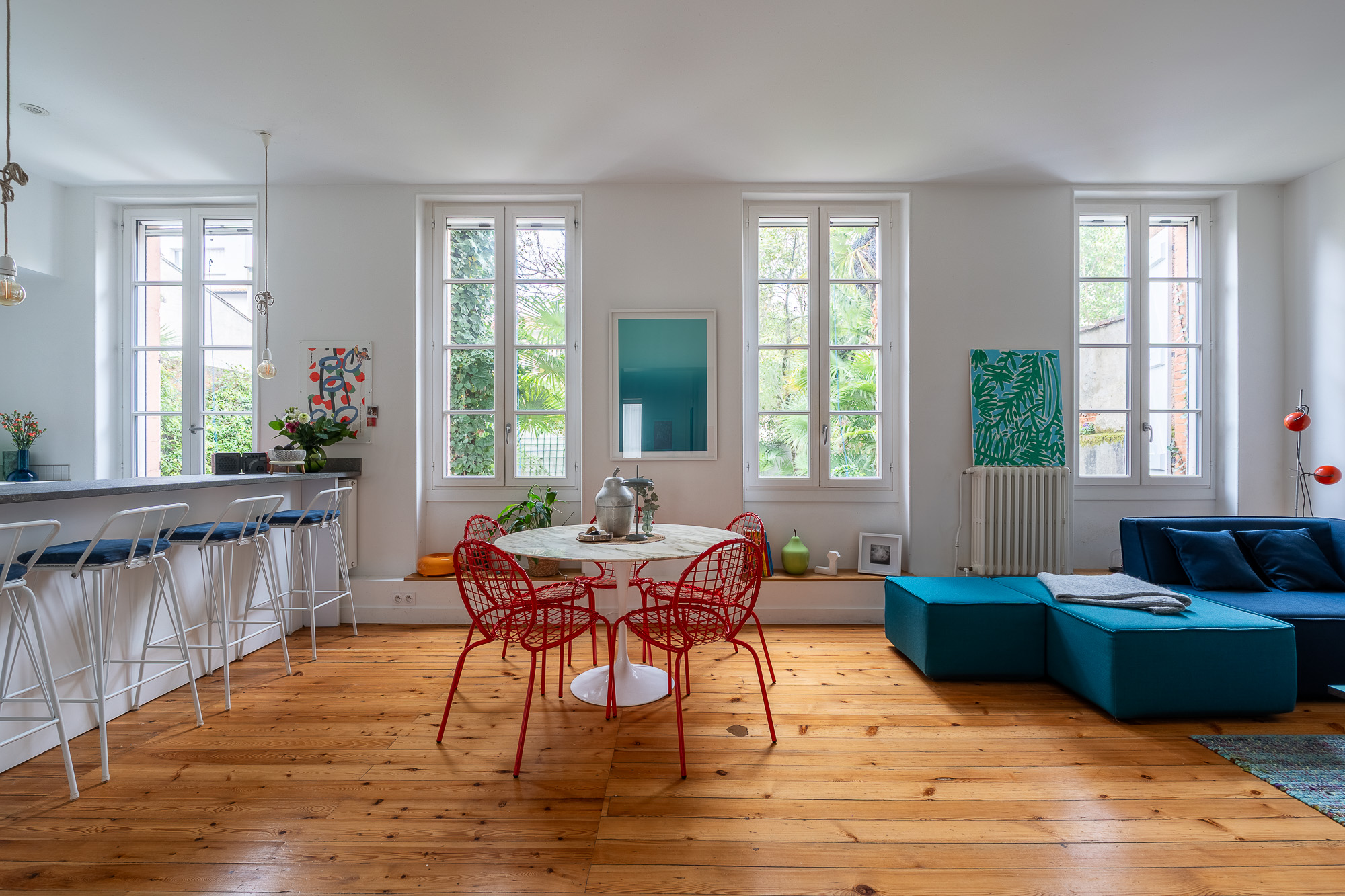 Grand séjour lumineux avec table Saarinen, chaises rouges et canapé bleu pétrole — rénovation appartement haussmannien Toulouse Merci Rose — reportage Pikimo