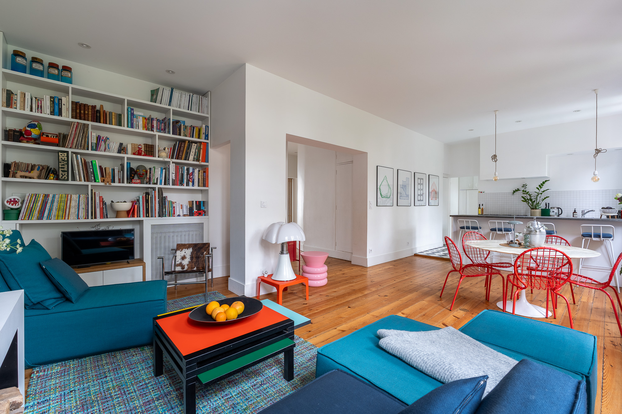 Salon avec bibliothèque sur mesure, canapés bleu pétrole et table basse colorée — appartement rénové Toulouse Merci Rose architecte d'intérieur — photographe Pikimo