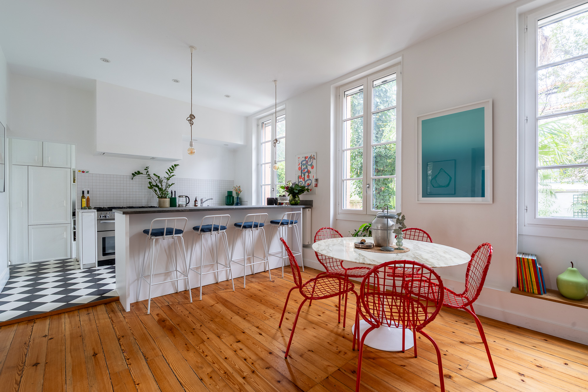 Cuisine ouverte avec îlot et table Saarinen chaises rouges sur parquet ancien — rénovation appartement Toulouse Merci Rose architecte d'intérieur — Pikimo