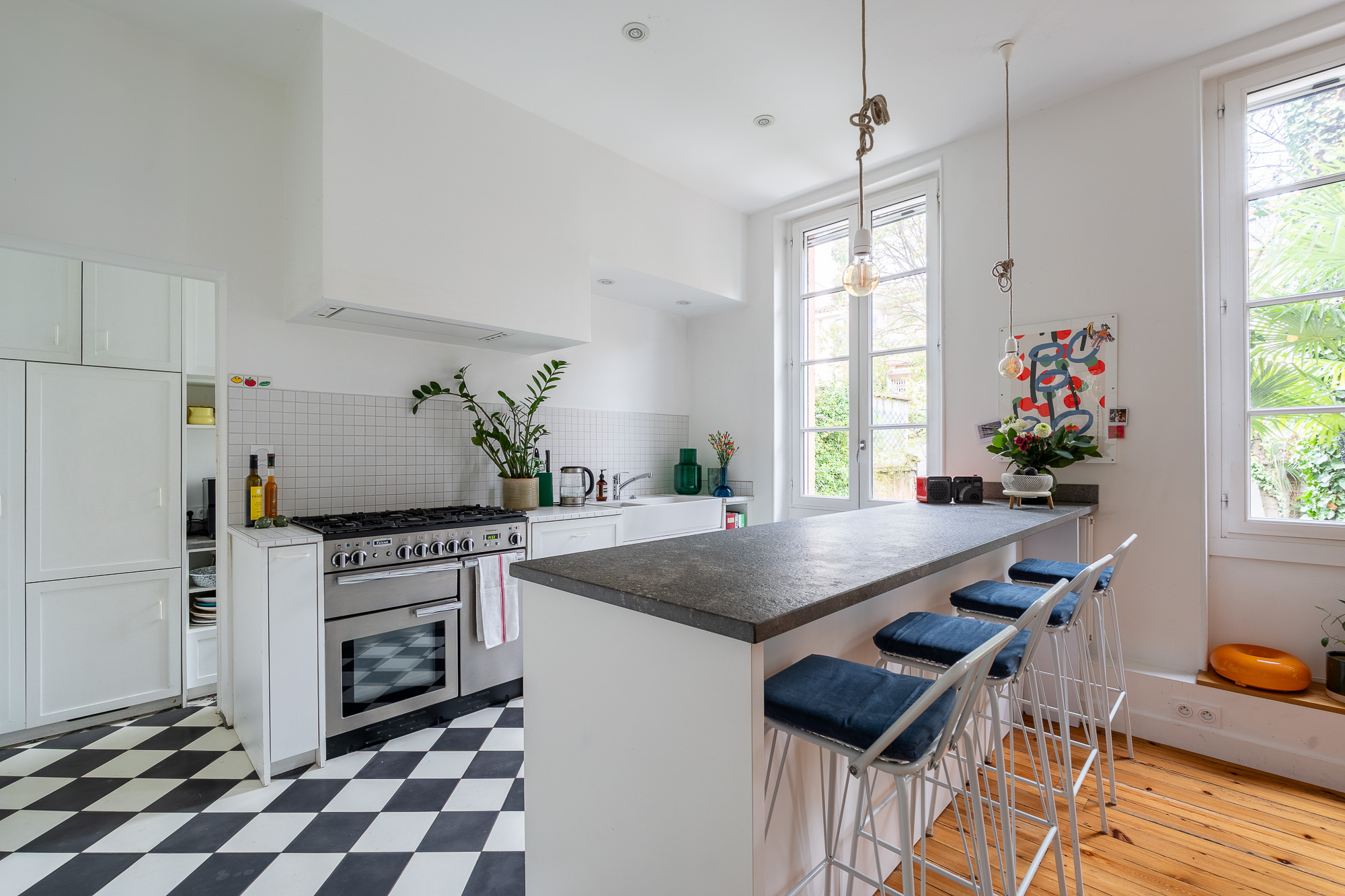 Cuisine avec piano de cuisson et carrelage damier noir et blanc — rénovation appartement haussmannien Toulouse Merci Rose architecte d'intérieur — reportage Pikimo