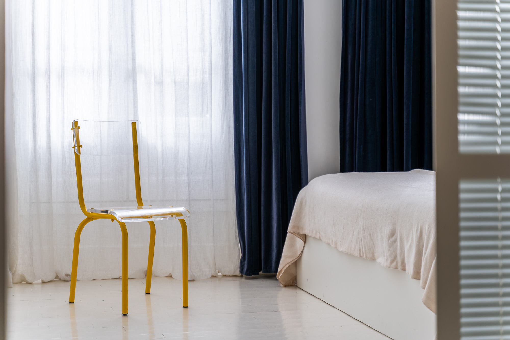 Chambre épurée avec rideaux bleu marine et chaise jaune translucide — rénovation appartement Toulouse Merci Rose architecte d'intérieur — reportage Pikimo