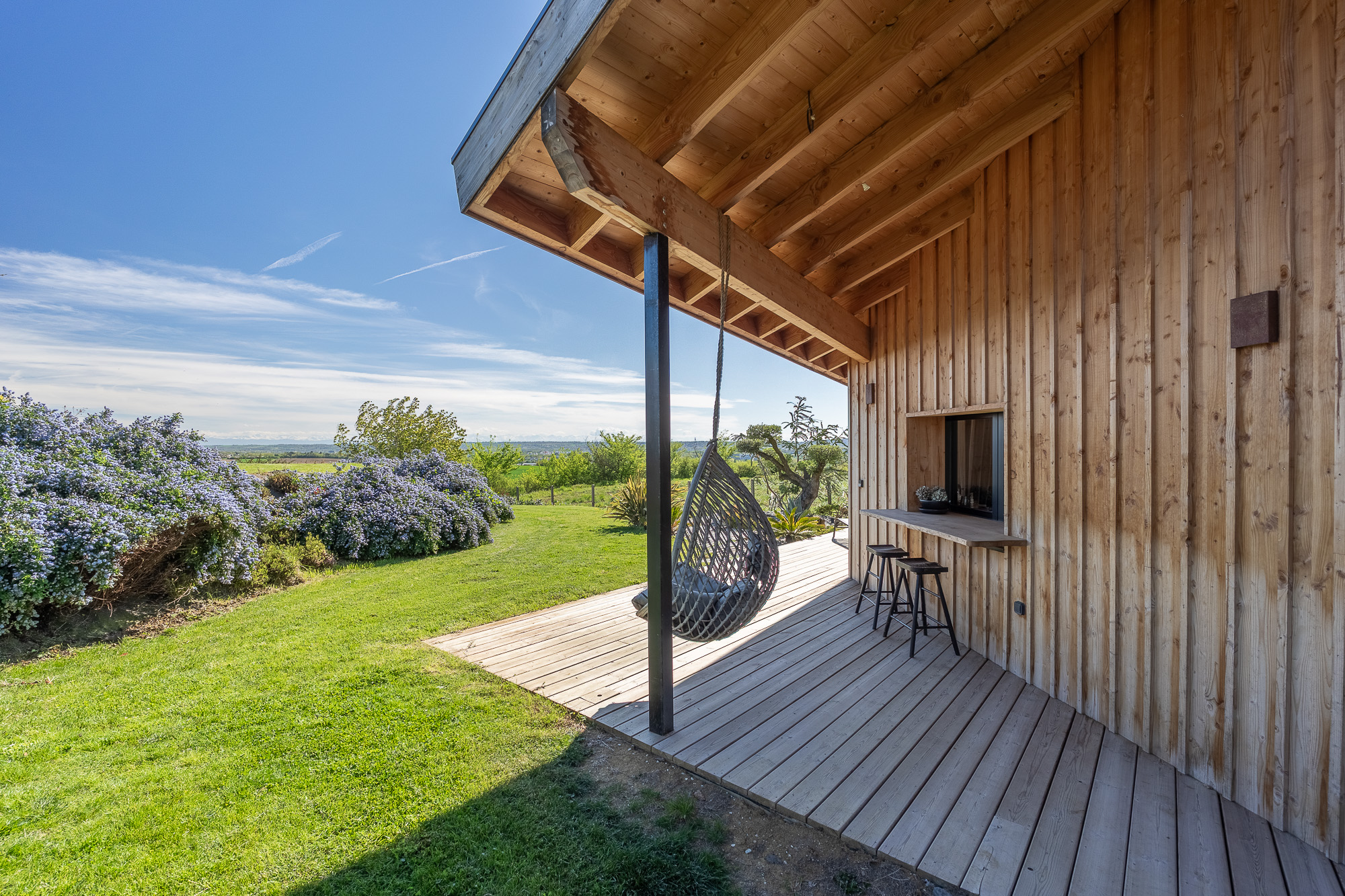Fauteuil suspendu et bar extérieur terrasse bois — gîte Nomad's Co Toulouse