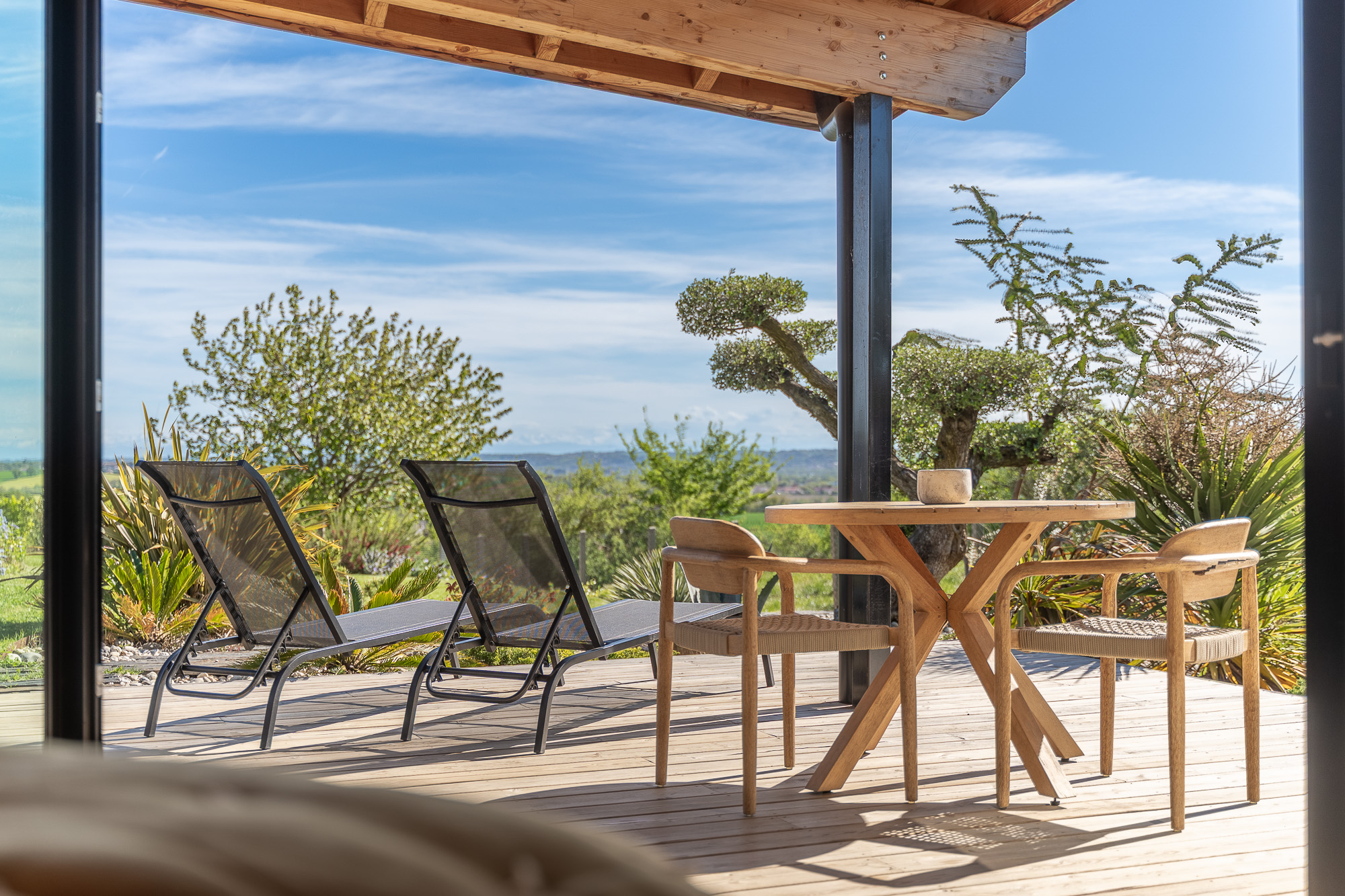 Vue terrasse table et transats sur jardin paysager — location Nomad's Co Toulouse