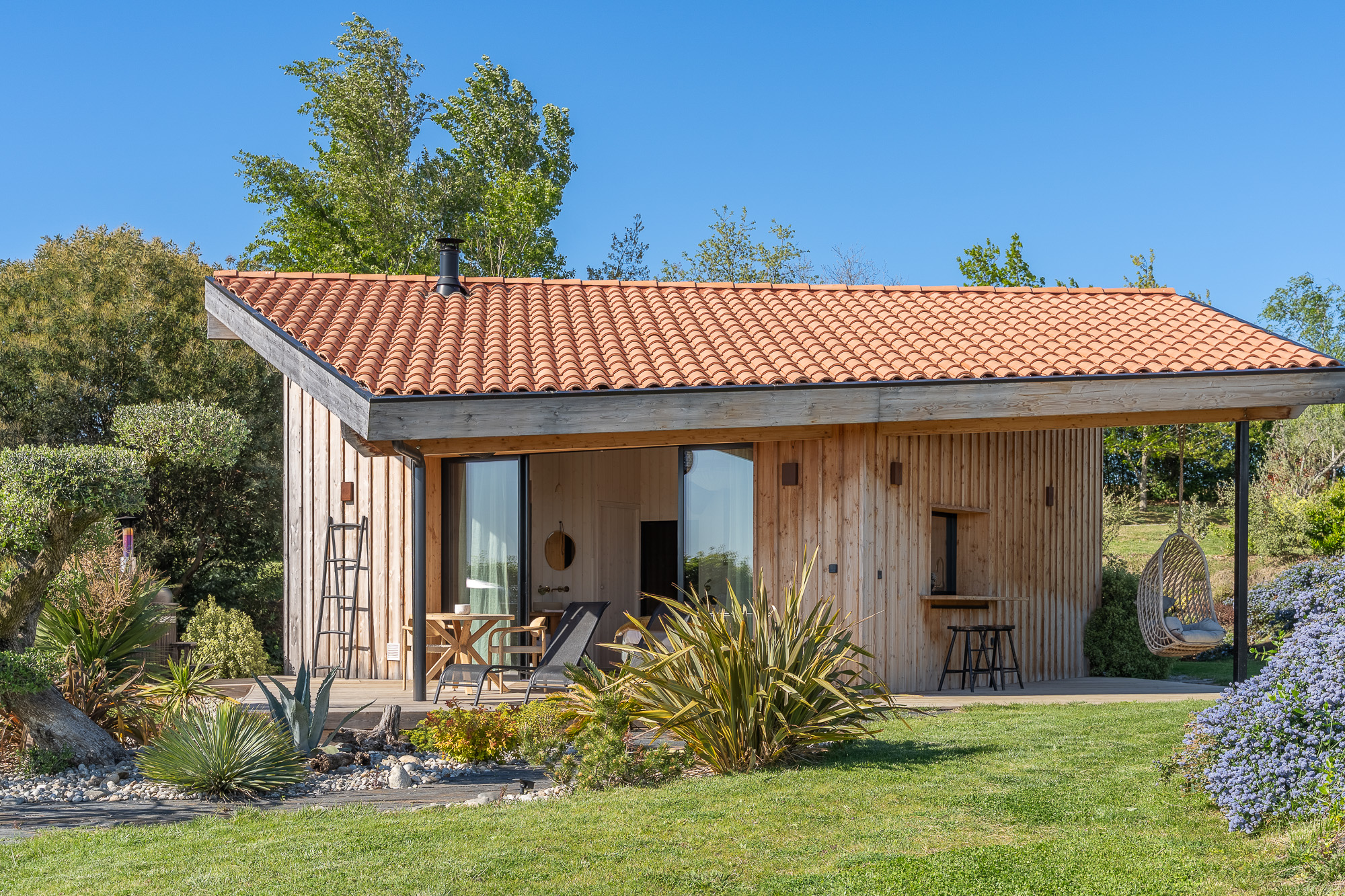 Façade gîte en bois avec fauteuil suspendu — location Airbnb Nomad's Co Toulouse