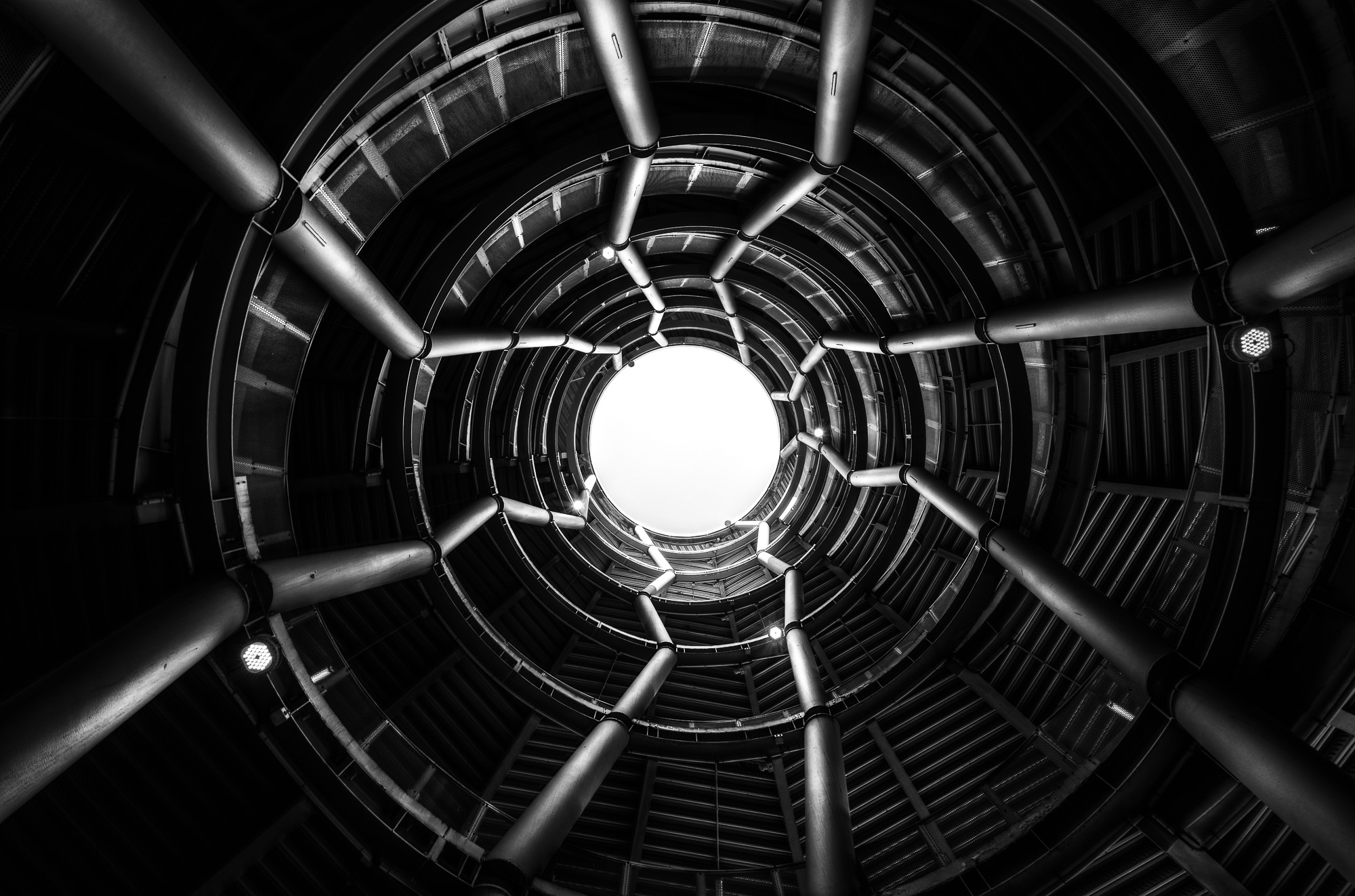 Vue en contre-plongée d'une structure architecturale circulaire en noir et blanc, ouverture lumineuse au centre — photographie Fine Art architecture Nicolas Pluquet Pikimo